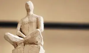 Nahe Aufnahme einer weißen Tonfigur in Sitzhaltung; Beispiel für ein Kunsttherapie‑Projekt.